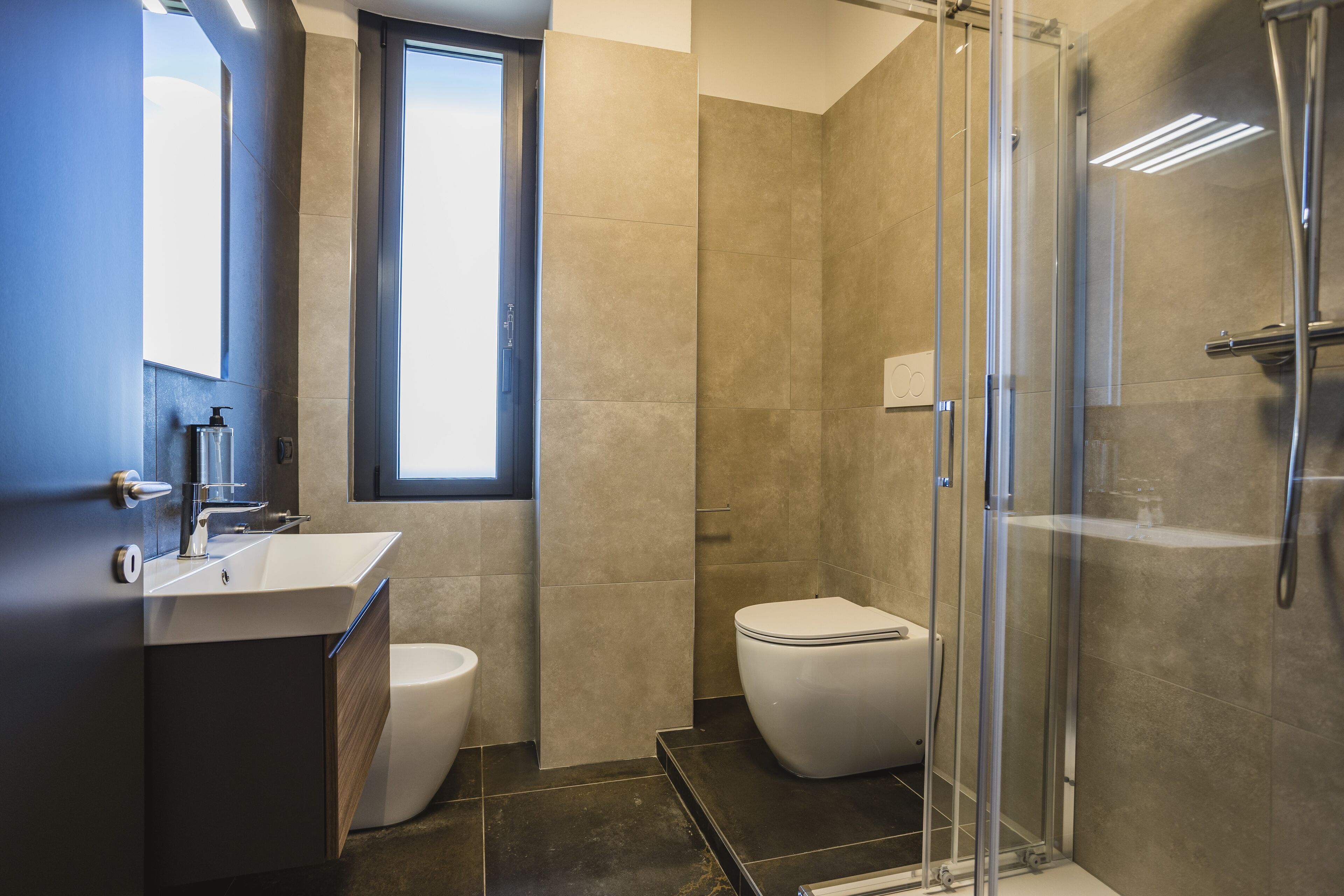 A modern bathroom with a glass shower enclosure, a toilet, and a sink with a mirror.