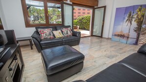 A modern living room with a leather sofa, ottoman, and a flat-screen TV.