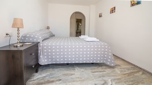 Una habitación de hotel con cama, cómoda, lámpara y obras de arte en las paredes.