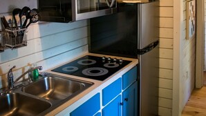 A kitchen with blue cabinets, stainless steel appliances, and a hanging light fixture. - Carowinds Camp Wilderness (Charlotte)