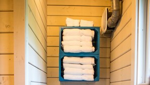 A compact bathroom with a white toilet, a blue soap dispenser, and a shelf with folded towels. - Carowinds Camp Wilderness (Charlotte)