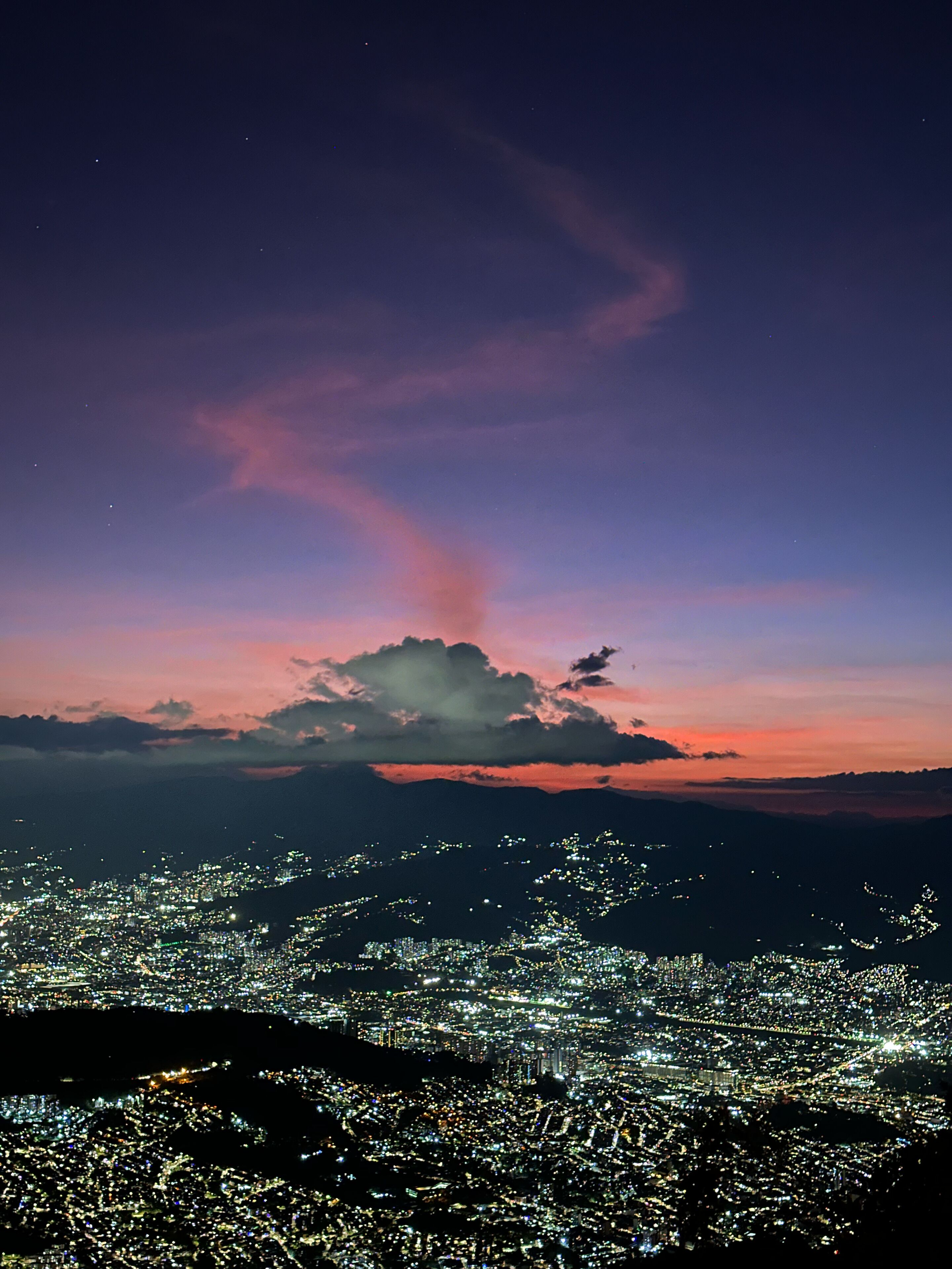 A nighttime cityscape with a prominent cloud formation in the sky.