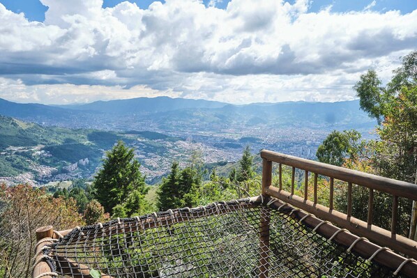 Un mirador panorámico con barandilla y red de seguridad, que ofrece vistas de la ciudad y montañas.