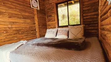 Una habitación de cabaña de madera con una cama, una ventana y un cartel en la pared.
