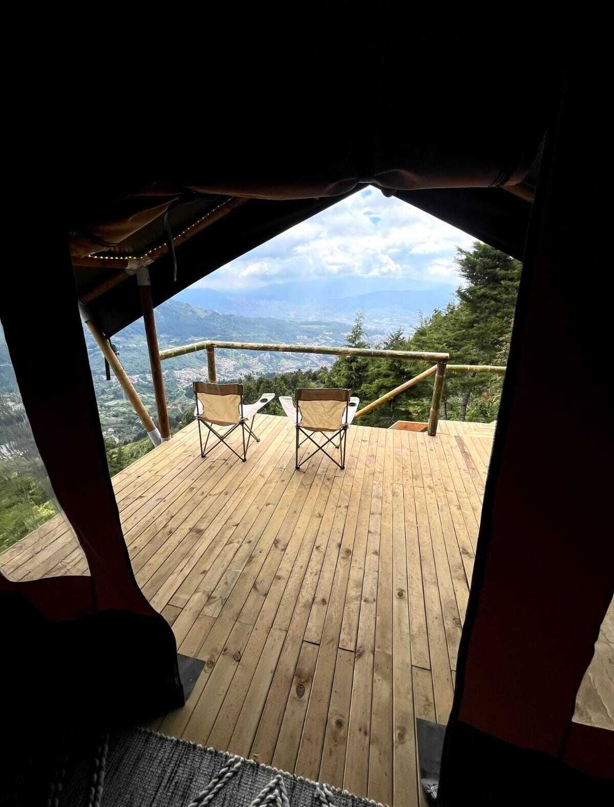 A wooden deck with two folding chairs facing a scenic view of mountains and a cloudy sky.