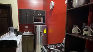 Cocina compacta con estufa, microondas, refrigerador y armarios.