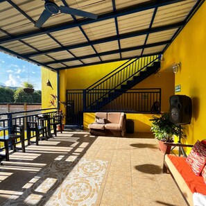 A covered outdoor seating area with a staircase, a sofa, and a speaker. - B. Apart Hotel (Roatan)