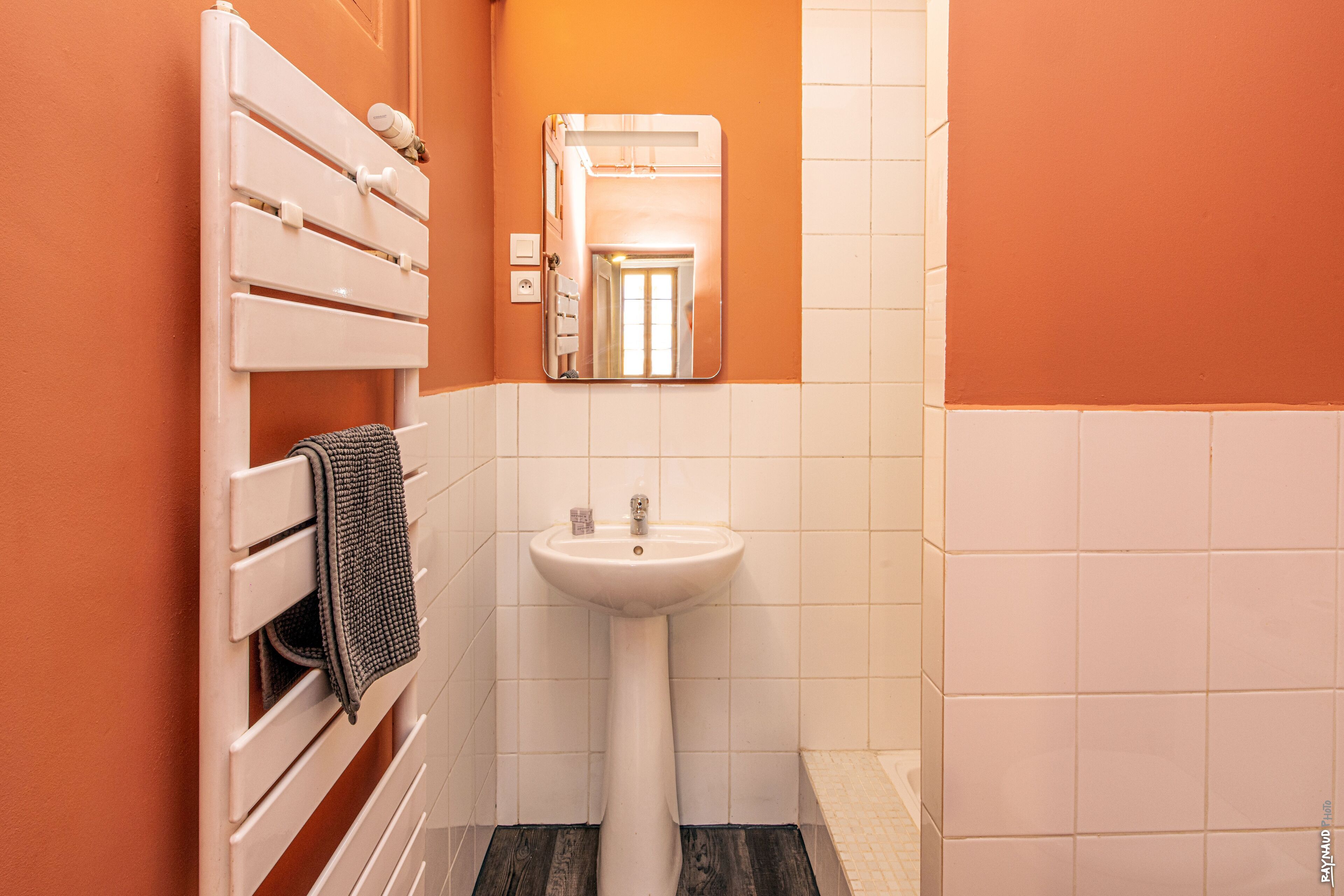 A bathroom with a white sink, a mirror, and a towel rack.