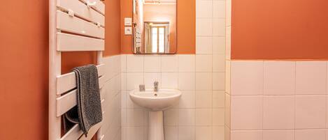 A bathroom with a white sink, a mirror, and a towel rack.
