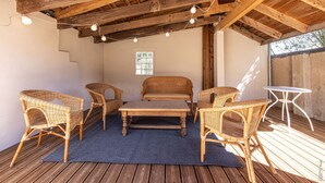 An outdoor patio area with wicker furniture, a wooden table, and string lights. - Maison 116 - Hypercentre - Gaillac (Gaillac)