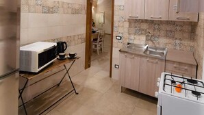 A compact kitchen with a microwave, coffee maker, and gas stove. There is a dining area visible through an open doorway. - Finely renovated apartment in the center of Grottaglie (Grottaglie)