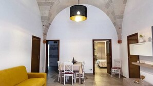A spacious living area with a yellow sofa, a dining table with chairs, and a hanging light fixture. - Finely renovated apartment in the center of Grottaglie (Grottaglie)