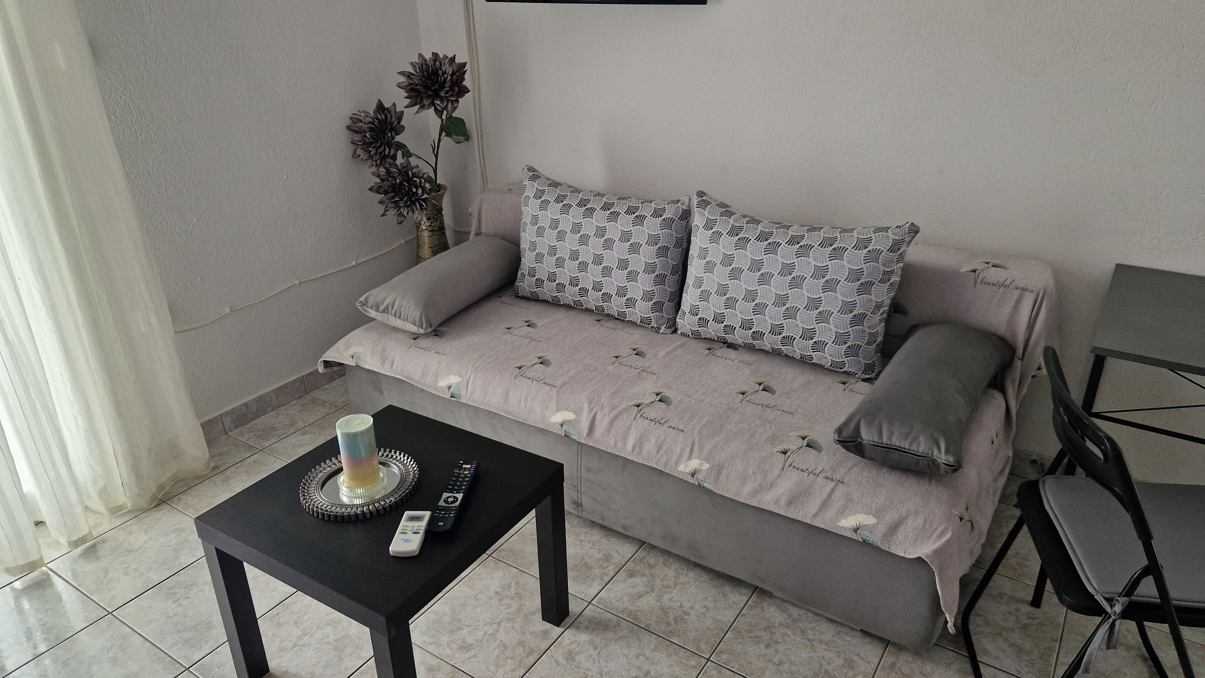 Een moderne woonkamer met een bank, gestreepte kussens, een klein tafeltje met een afstandsbediening en een decoratieve vaas.