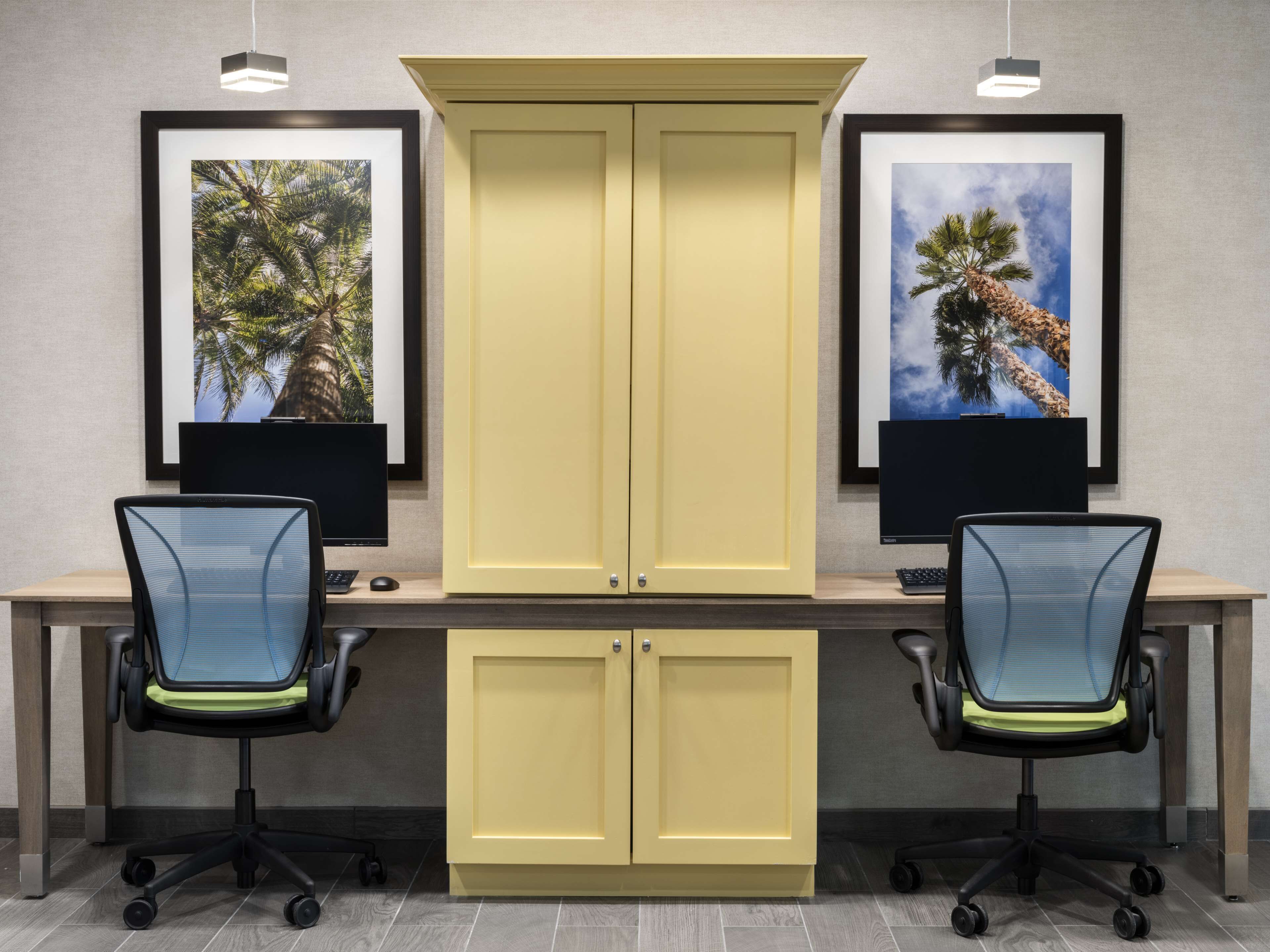 A workspace with two desks, each with a computer monitor, keyboard, and office chair.