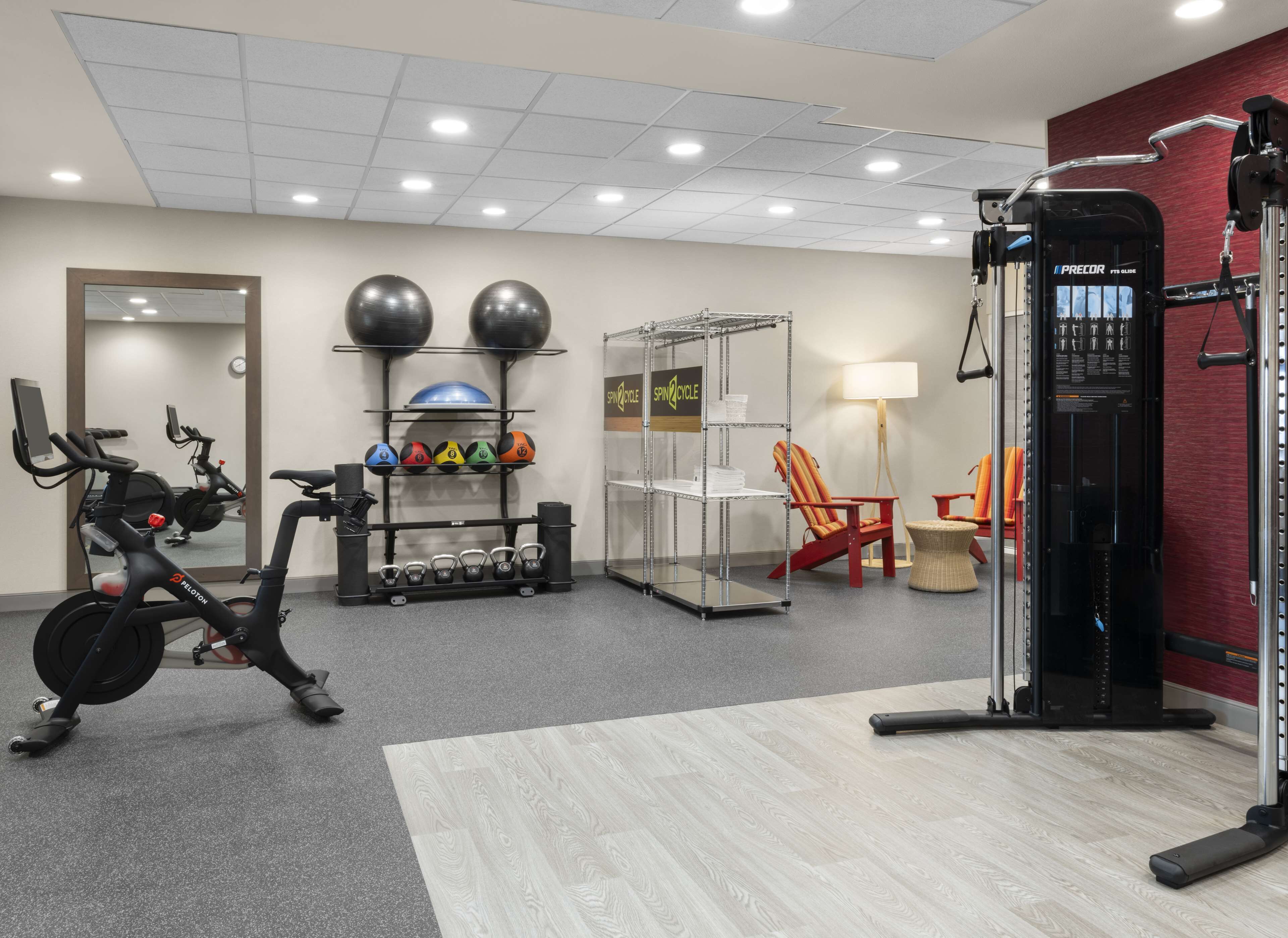 Une salle de sport équipée de matériel d’exercice, notamment un vélo de spinning, des kettlebells et un support pour les exercices de squat.