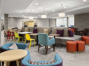 A modern lounge area with seating arrangements, tables, and pendant lighting. - Home2 Suites by Hilton Orlando South Davenport (Davenport)