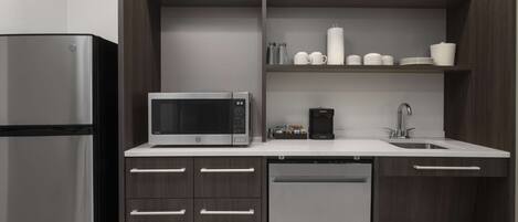 A modern kitchen with a stainless steel refrigerator, a built-in microwave, a coffee maker, and a dishwasher.