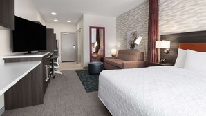Una habitación de hotel moderna con televisión de pantalla plana, un sofá, una cama y un escritorio con ordenador.