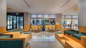 A modern lobby with seating areas, a reception desk, and large windows offering views of the outside. - Hilton Garden Inn Guangzhou Airport Aerotropolis (Guangzhou)