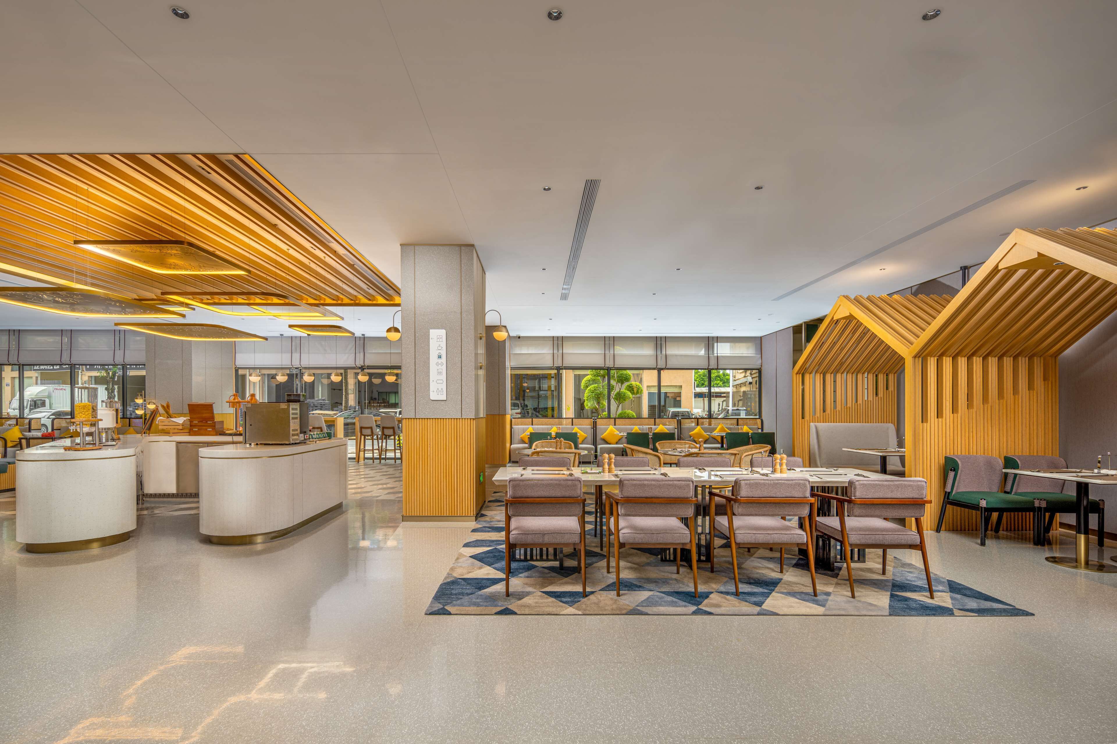 A modern hotel lobby with a central seating area, a reception desk, and a view of the outdoors.
