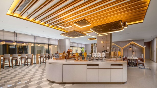 A modern hotel lobby with a central bar area, seating arrangements, and a check-in counter. - Hilton Garden Inn Guangzhou Airport Aerotropolis (Guangzhou)