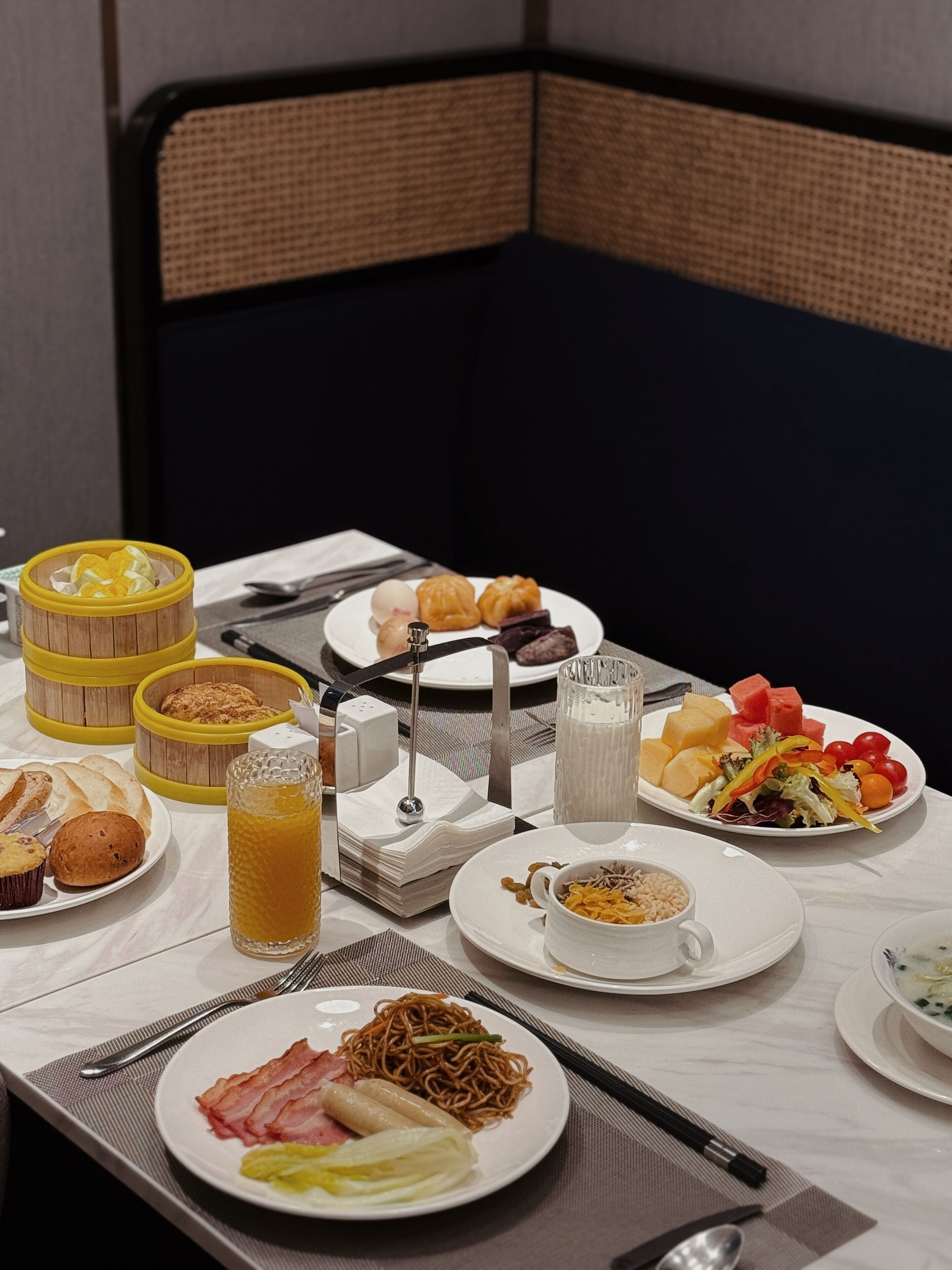 A breakfast buffet with various dishes including bread, pastries, and a fruit salad.
