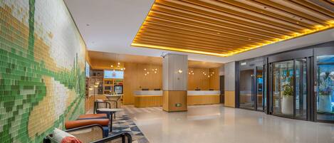 A modern lobby with a reception desk, seating area, and a patterned wall.