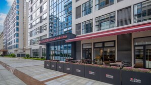 A Hilton Garden Inn with a modern facade, large windows, and outdoor seating area. - Hilton Garden Inn Guangzhou Airport Aerotropolis (Guangzhou)