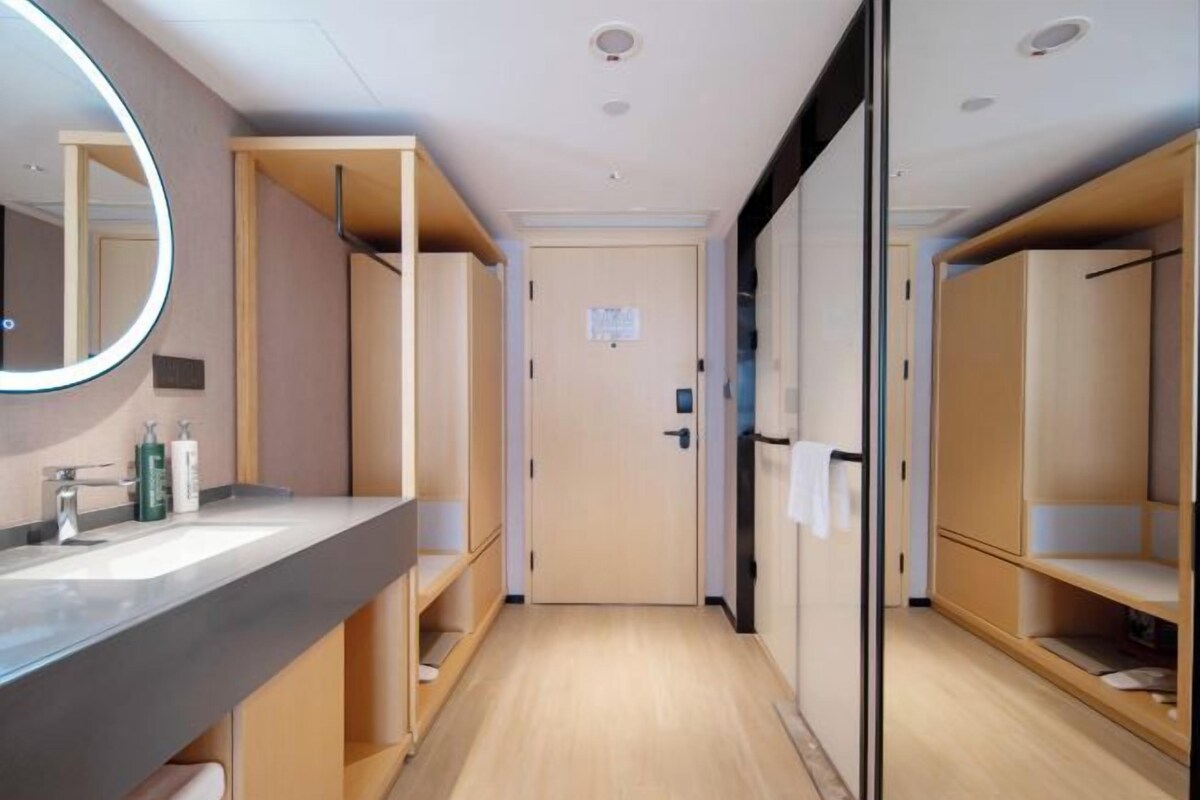 A modern bathroom with a large mirror, a sink, and wooden cabinets.