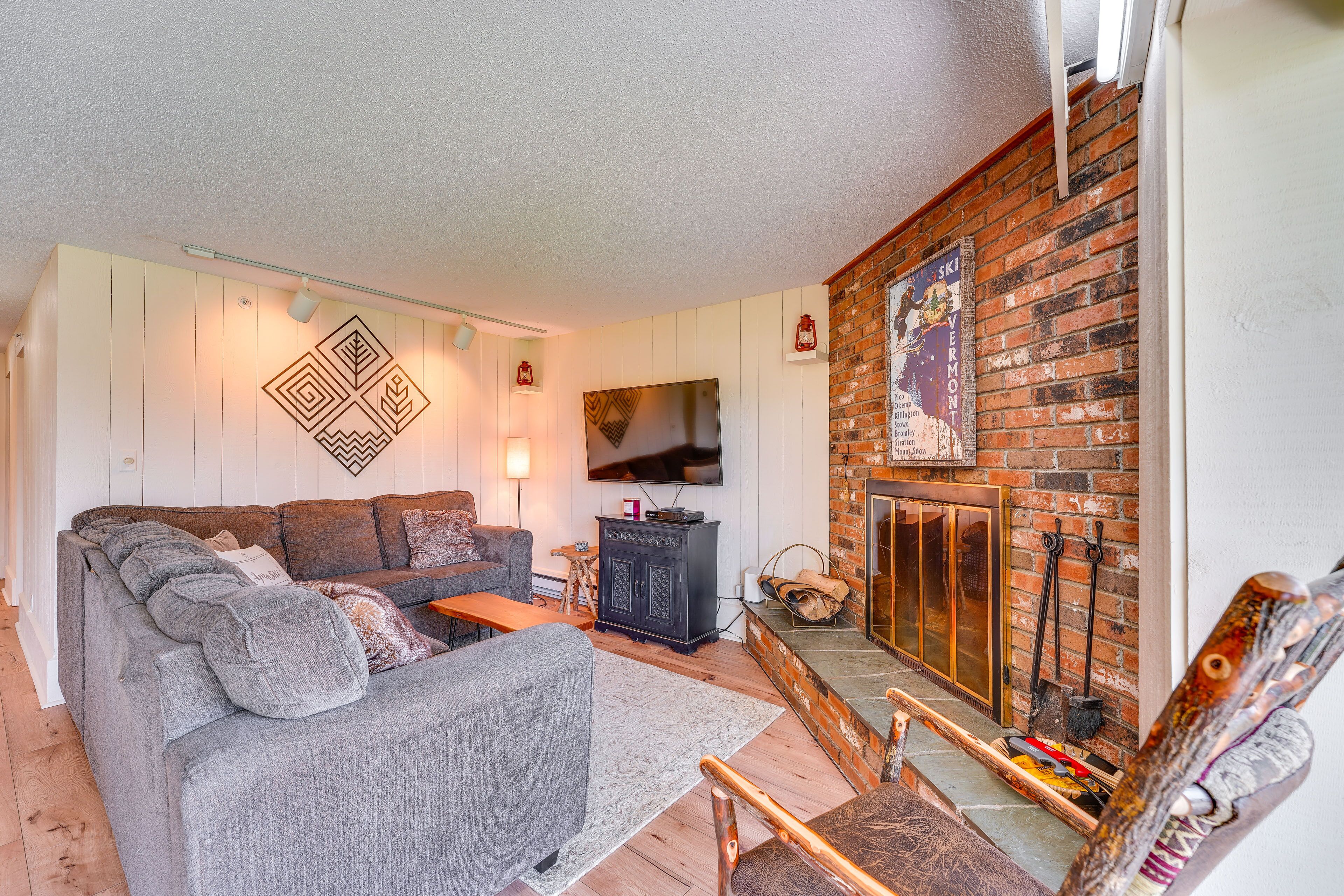 Una sala de estar acogedora con sofá, televisor, chimenea y pared de ladrillo.