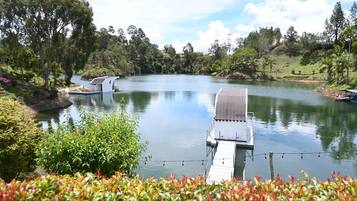 A serene lakeside setting with a dock extending into the water, surrounded by lush greenery and trees.