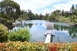 A serene lakeside setting with a dock extending into the water, surrounded by lush greenery and trees. - La trinidad (Guatapé)