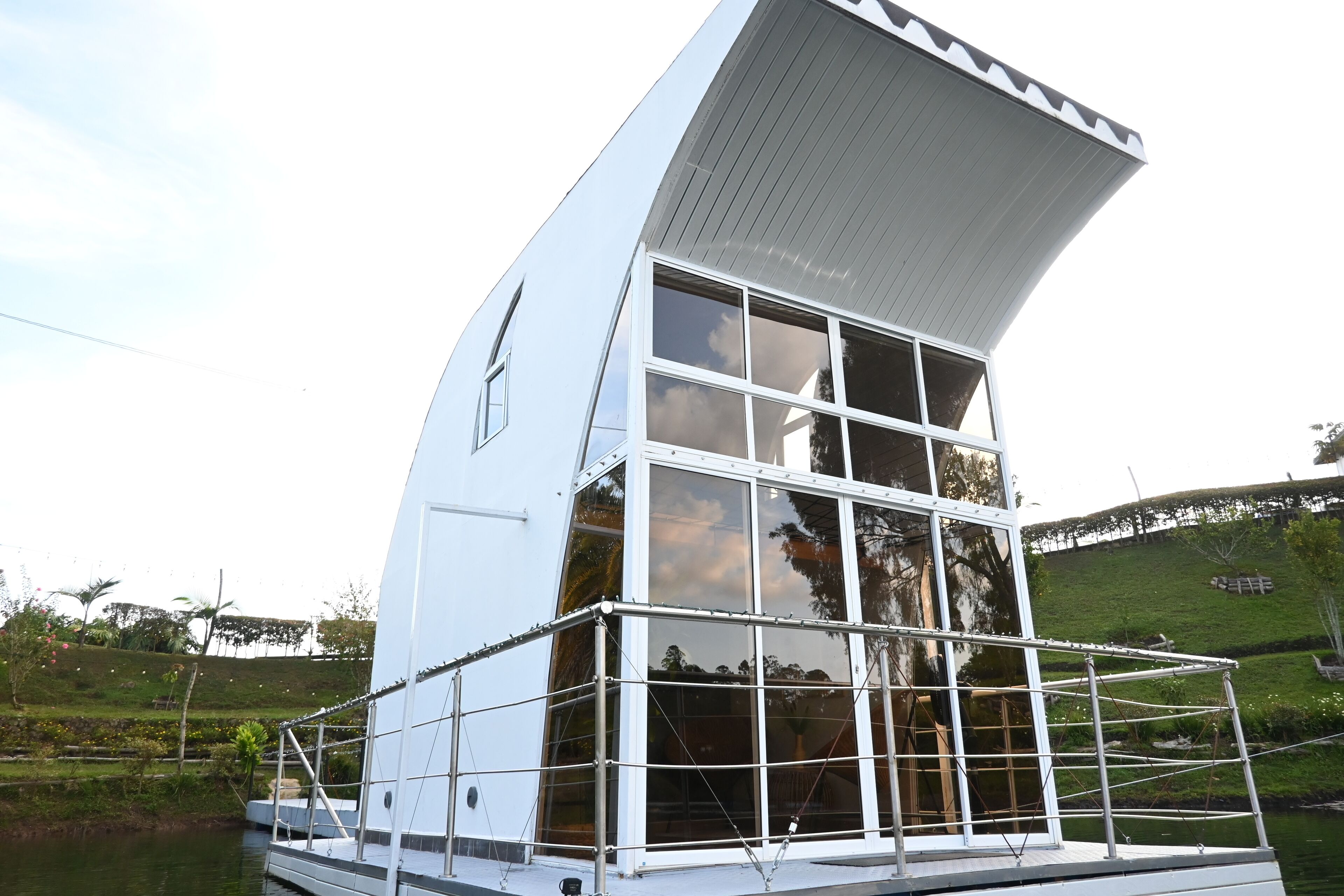 A modern, white, multi-story building with large windows and a curved roof, situated by a body of water.