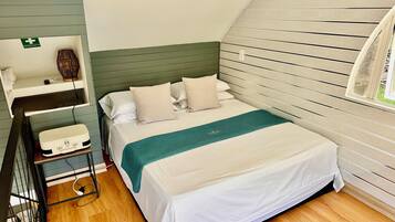 A neatly arranged bedroom with a bed, bedside table, and a shelf with a first aid kit.