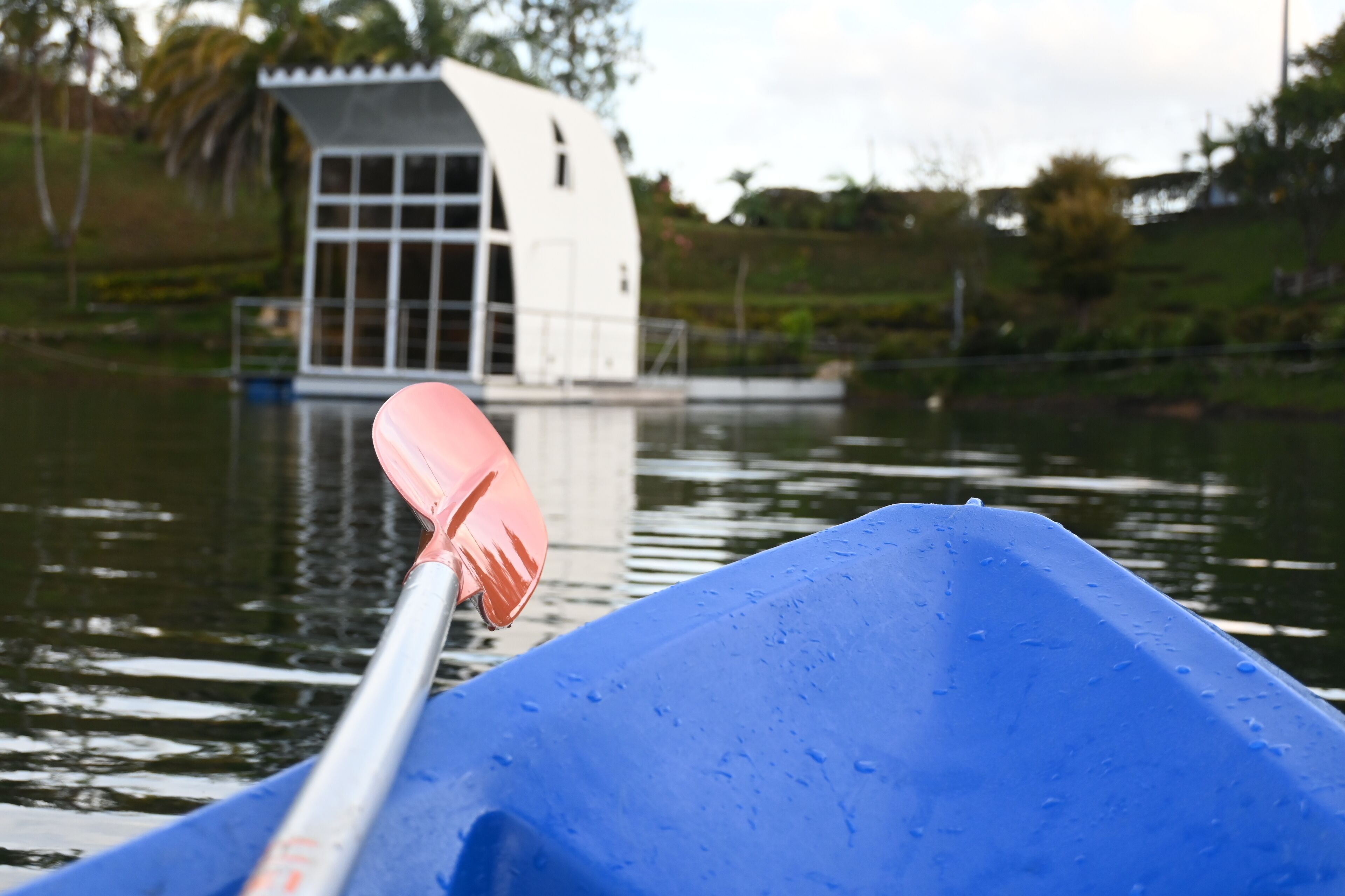 A blue canoe with a paddle on the water.
