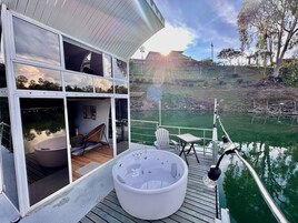 Una casa moderna con jacuzzi en una terraza con vista a un estanque.