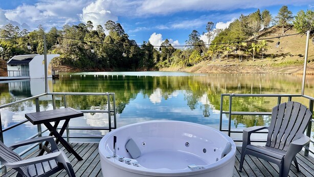 A hot tub on a wooden deck with a view of a lake and trees. - La trinidad (Guatapé)