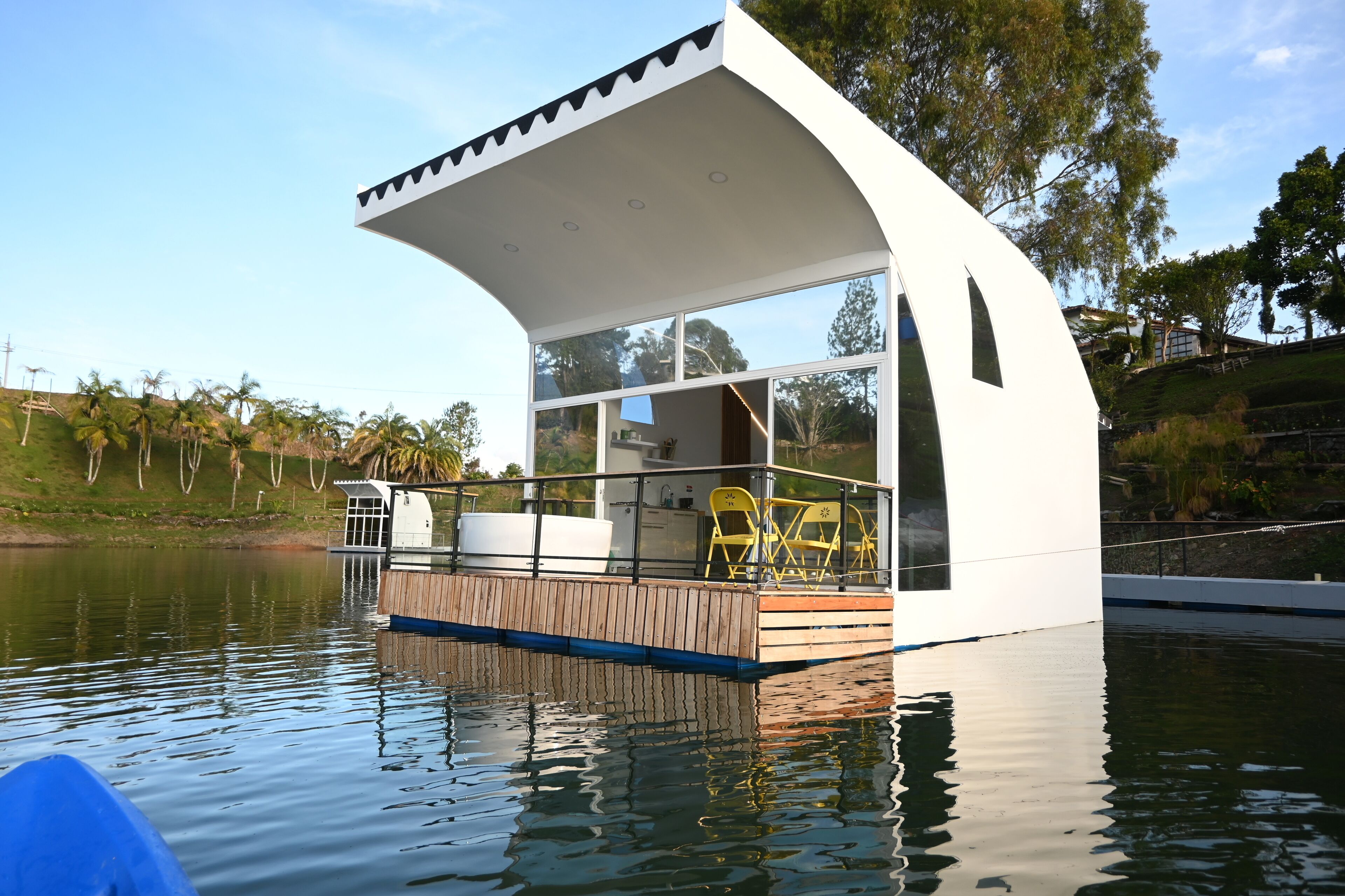 Una casa flotante moderna con techo curvo, ventanas amplias y terraza de madera.
