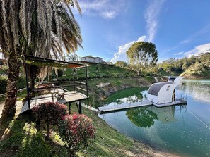 A serene riverside setting with a wooden deck and a white floating structure. - La trinidad (Guatapé)