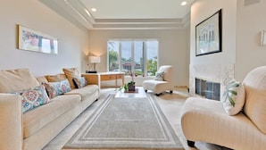 A spacious living room with a large window, a sofa set, a coffee table, and a fireplace. - Walk to Village/Beach/A/C/EV Charger/Parking (La Jolla)