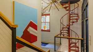 Un escalier avec une rampe rouge et un mur bleu orné d’un motif géométrique.
