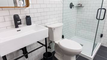 A modern bathroom with a white sink, black faucet, and a glass shower enclosure.