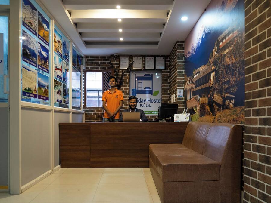 Un área de recepción con un escritorio de madera, un sofá marrón y una pared decorada con carteles y un mural.