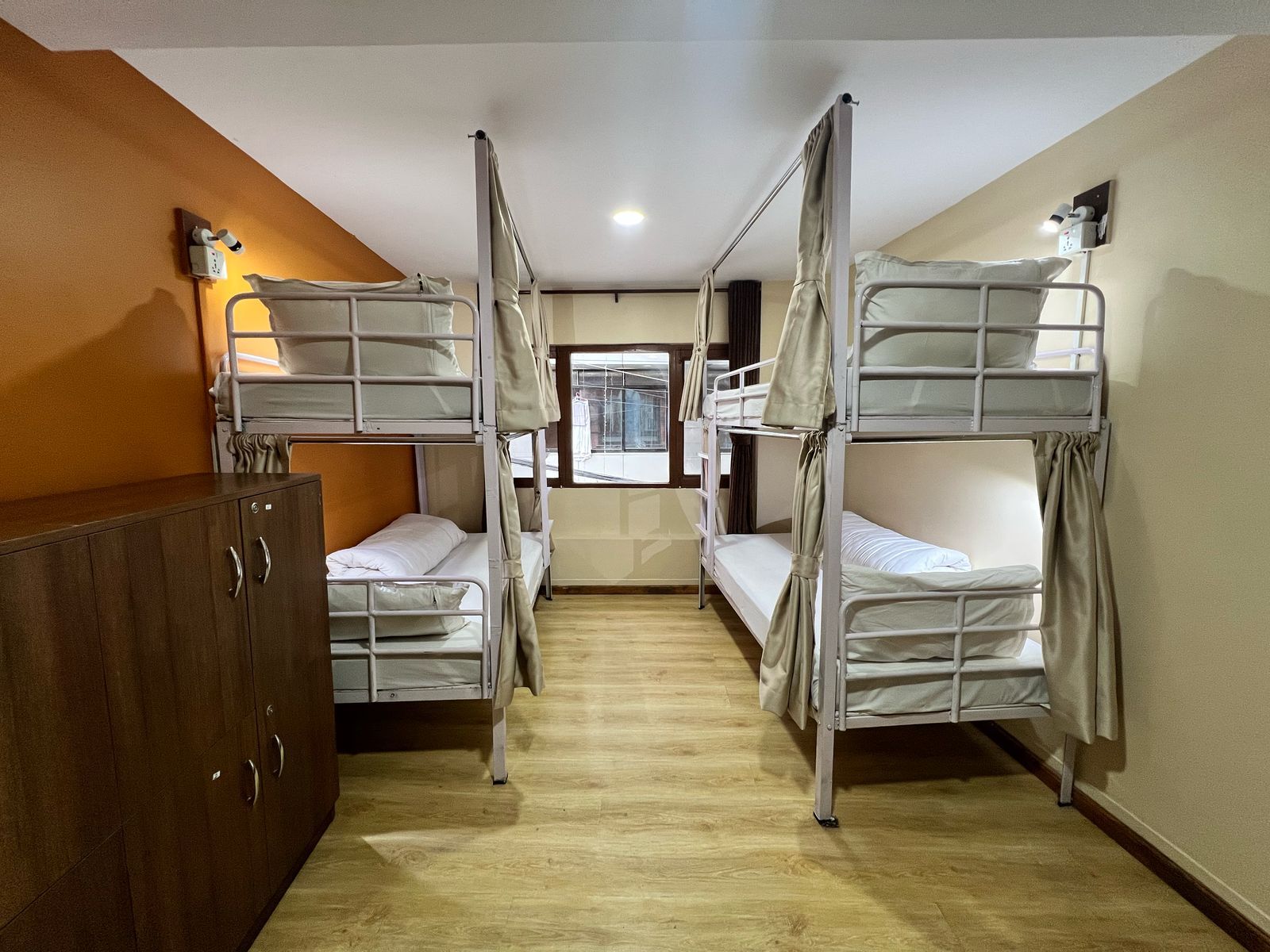 A room with bunk beds, a wooden wardrobe, and a window with a view.
