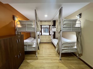A room with bunk beds, a wooden wardrobe, and a window with a view. - Holiday Hostel (Kathmandu)