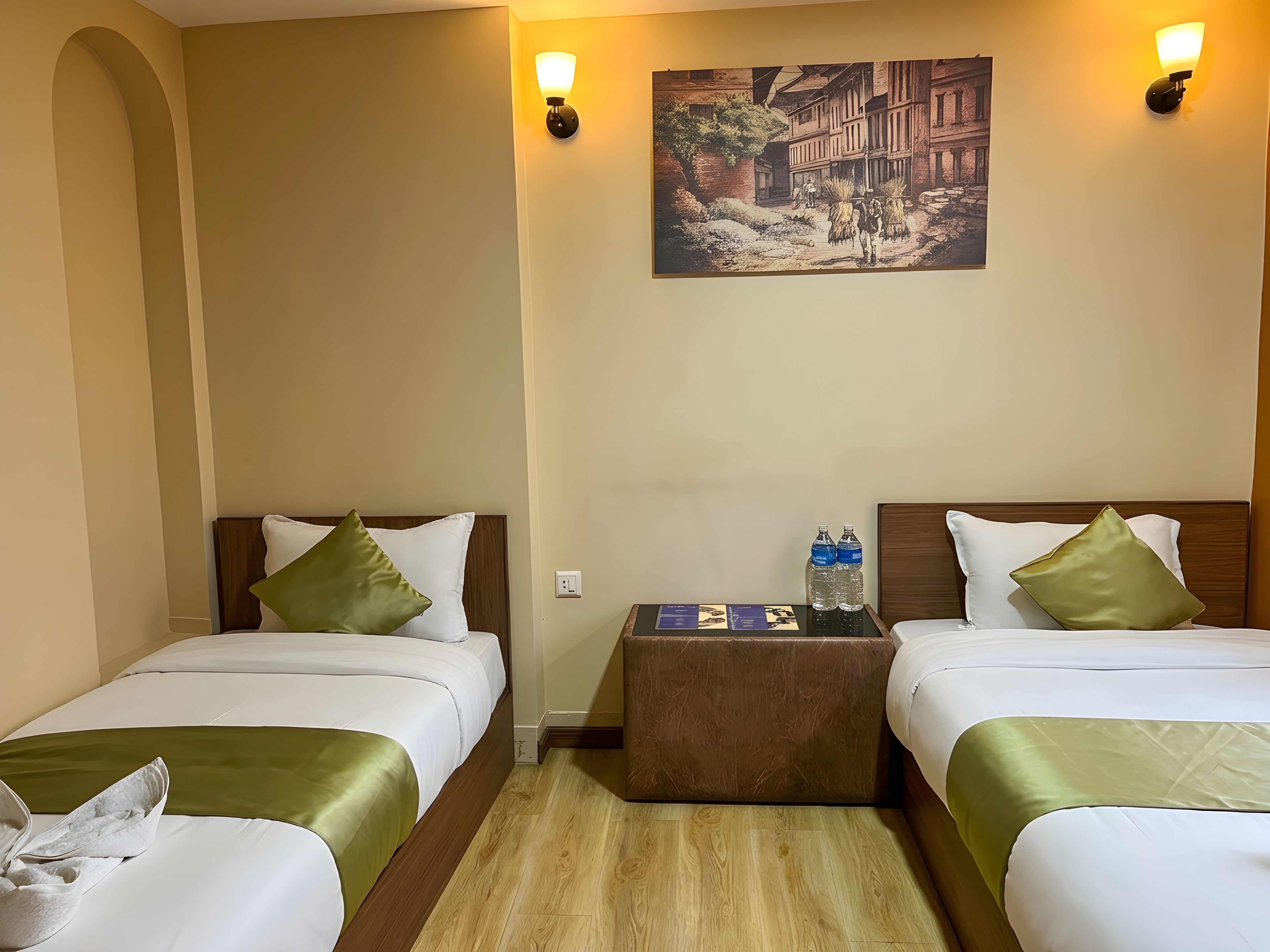 A hotel room with two beds, a nightstand, and a wall-mounted painting.