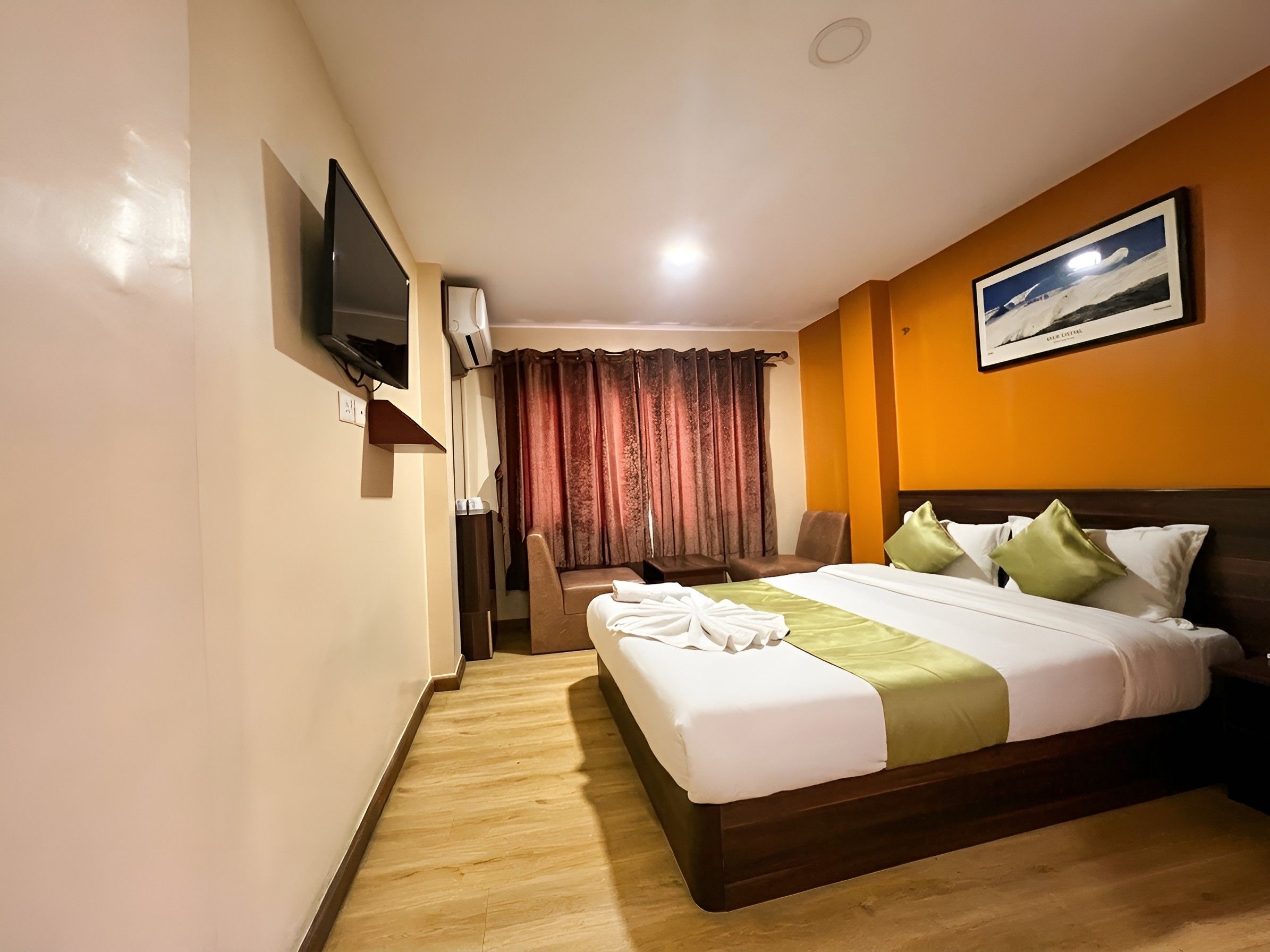 Habitación de hotel con cama, escritorio, silla, televisor y un cuadro en la pared.