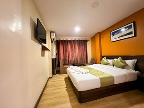 Une chambre d’hôtel avec un lit, un bureau, une chaise, une télévision et un tableau au mur.