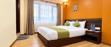 A hotel room with a bed, bedside table, and a wall-mounted lamp.