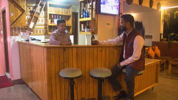 Una zona de bar con taburetes de madera, una barra y un televisor montado en la pared.